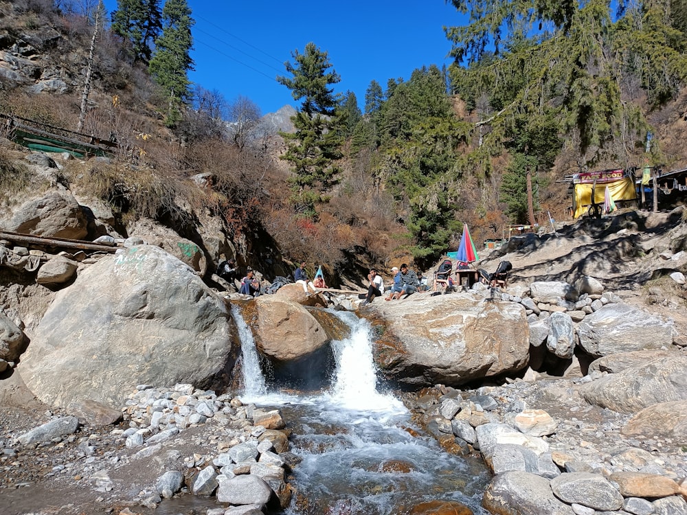 a group of people standing around a waterfall