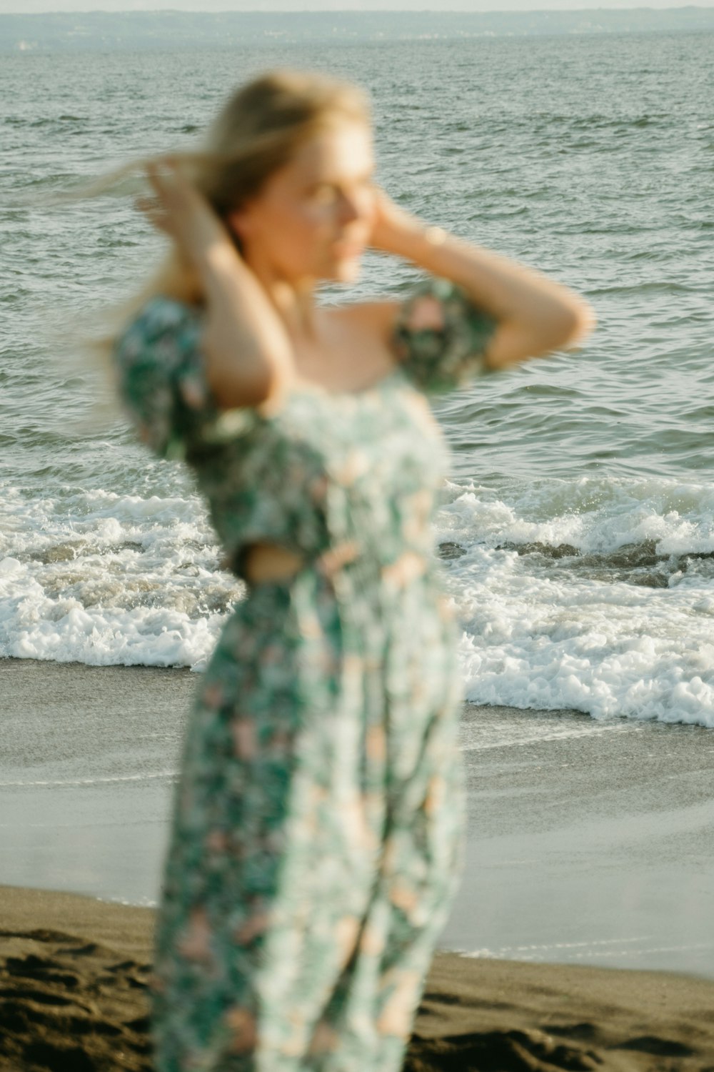 eine Frau, die an einem Strand neben dem Meer steht