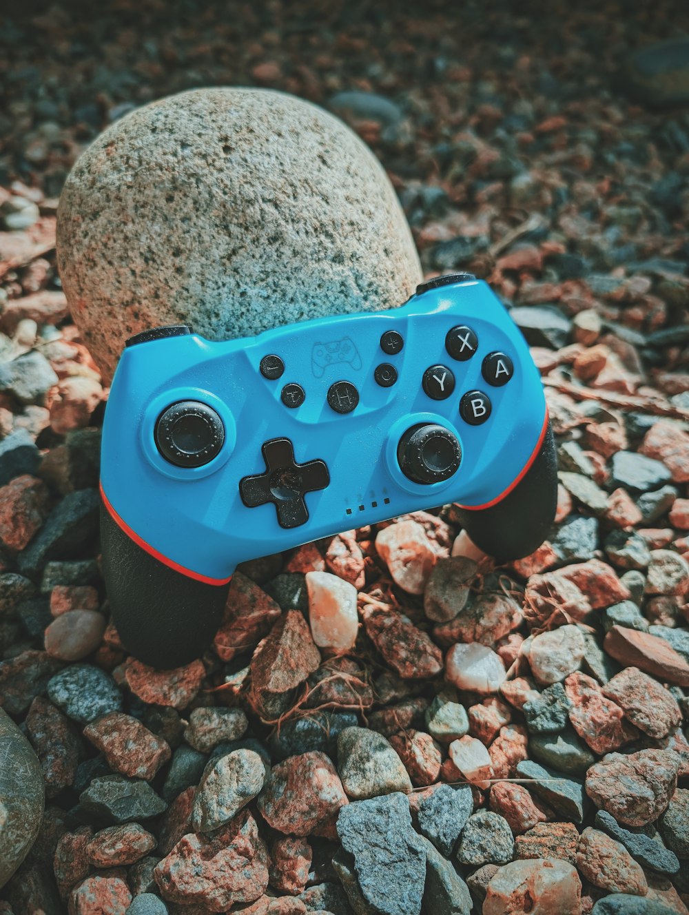 a blue controller sitting on top of a pile of rocks