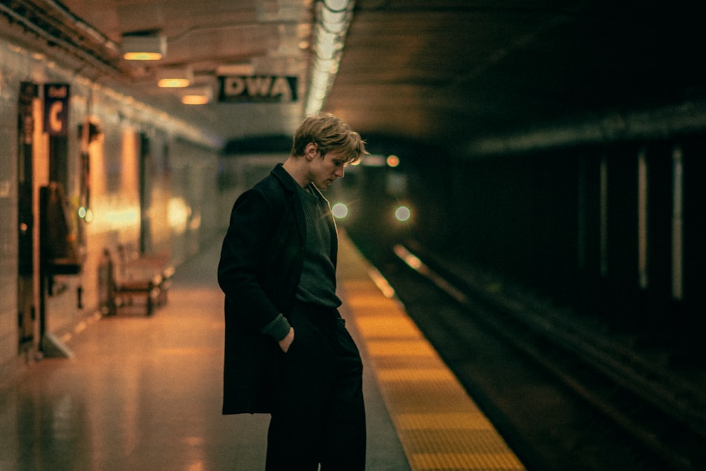 a man standing in a subway station waiting for a train