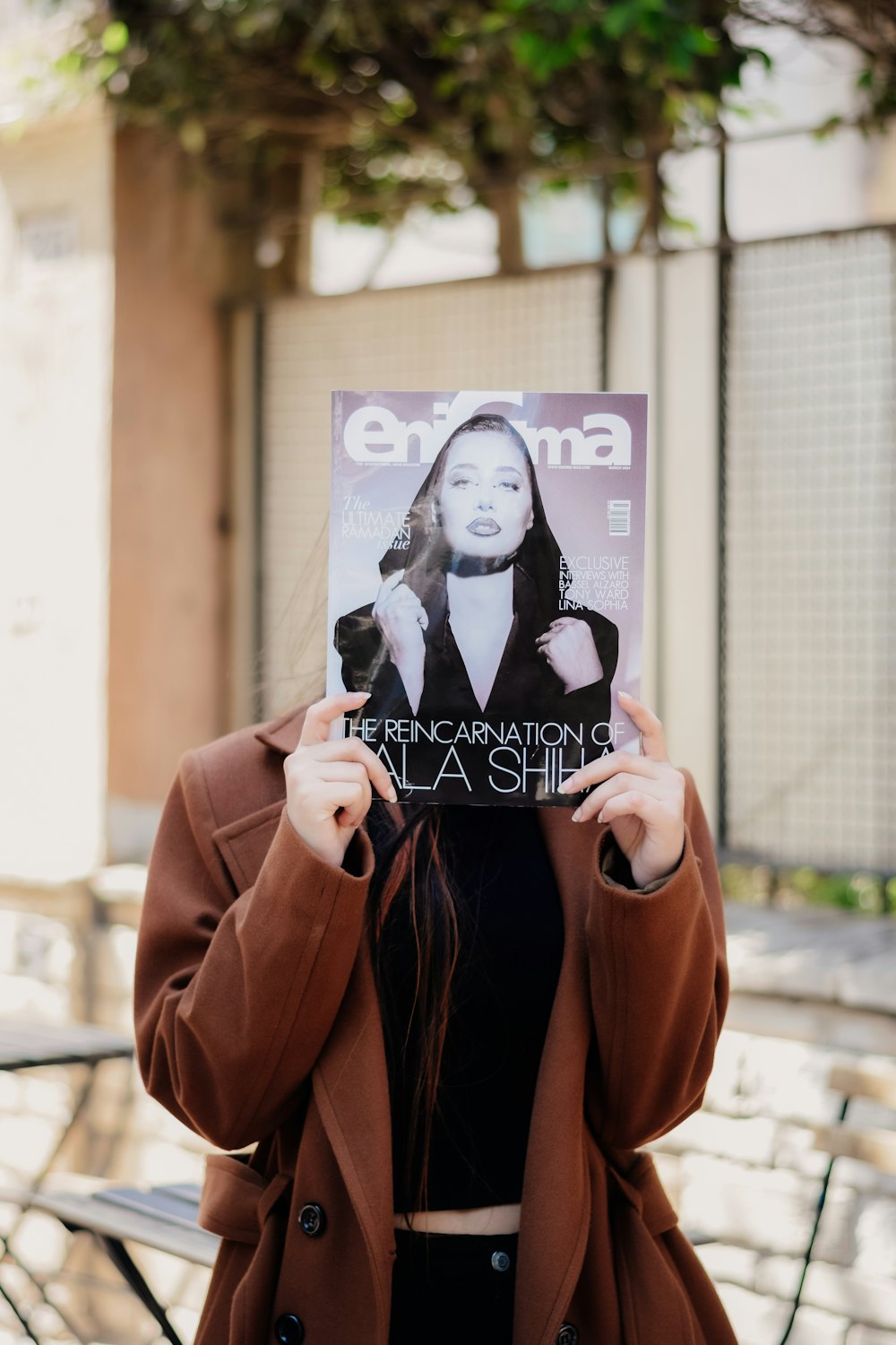 a woman holding up a magazine in front of her face