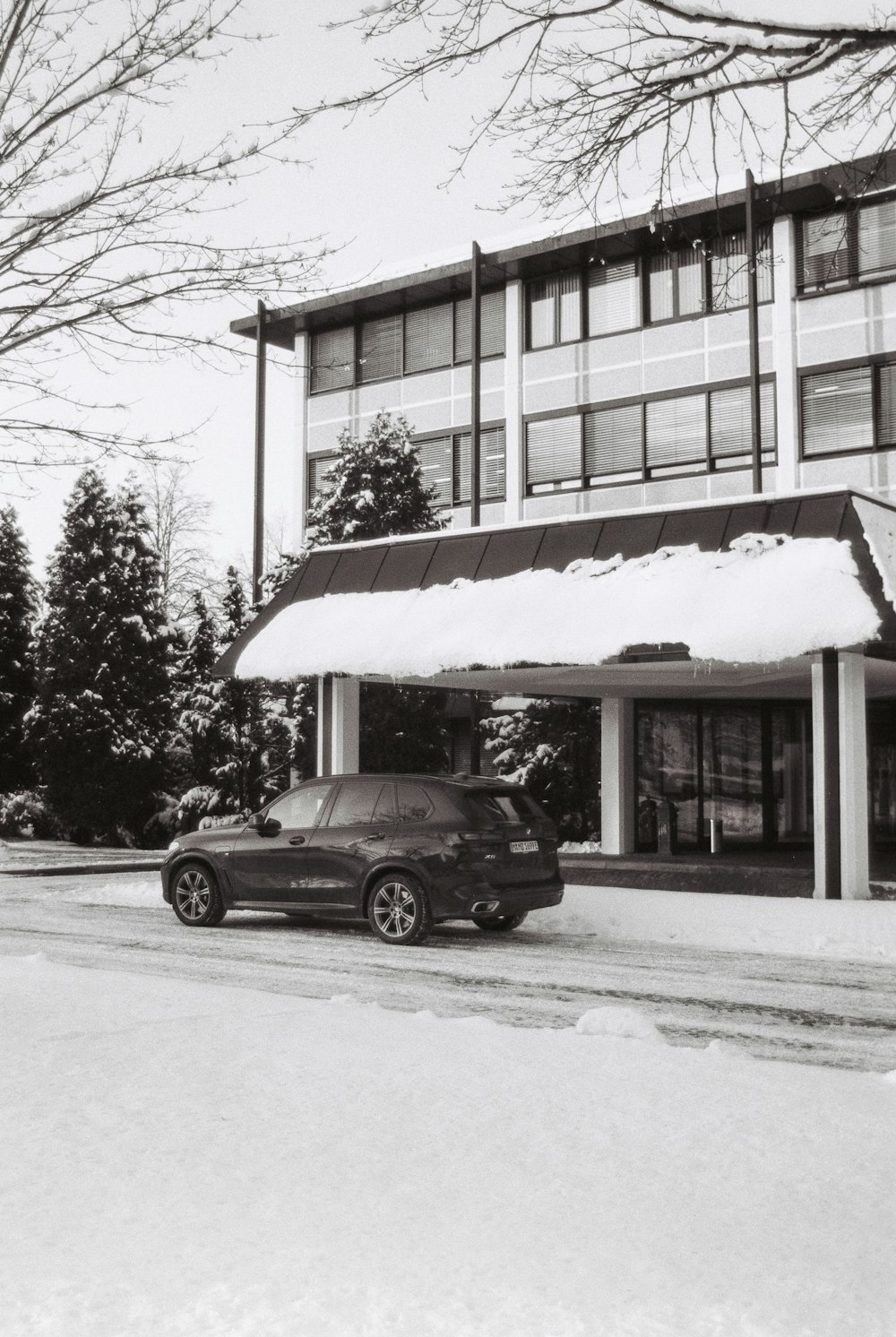 a black and white photo of a building with a car parked in front of it
