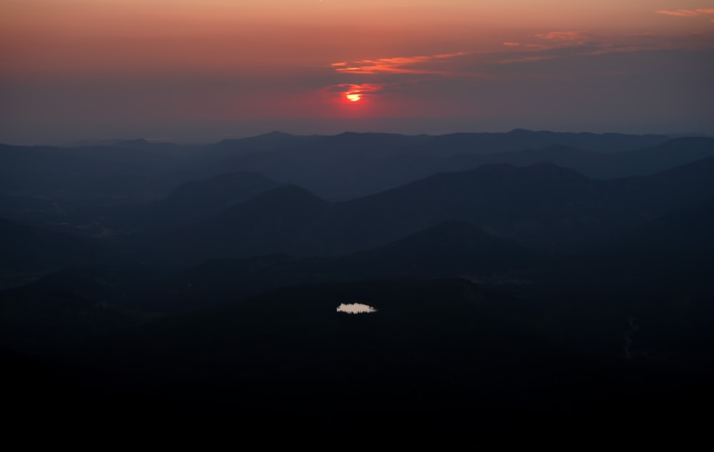 the sun is setting over a mountain range