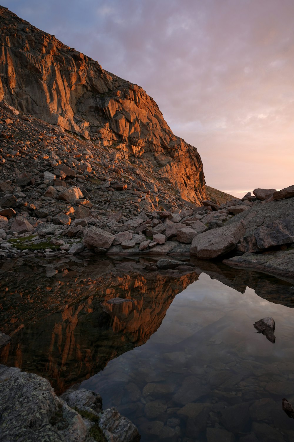 a rocky mountain with a body of water in the foreground