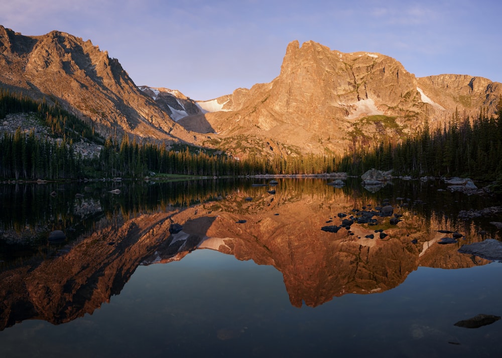 a mountain range is reflected in the still water of a lake