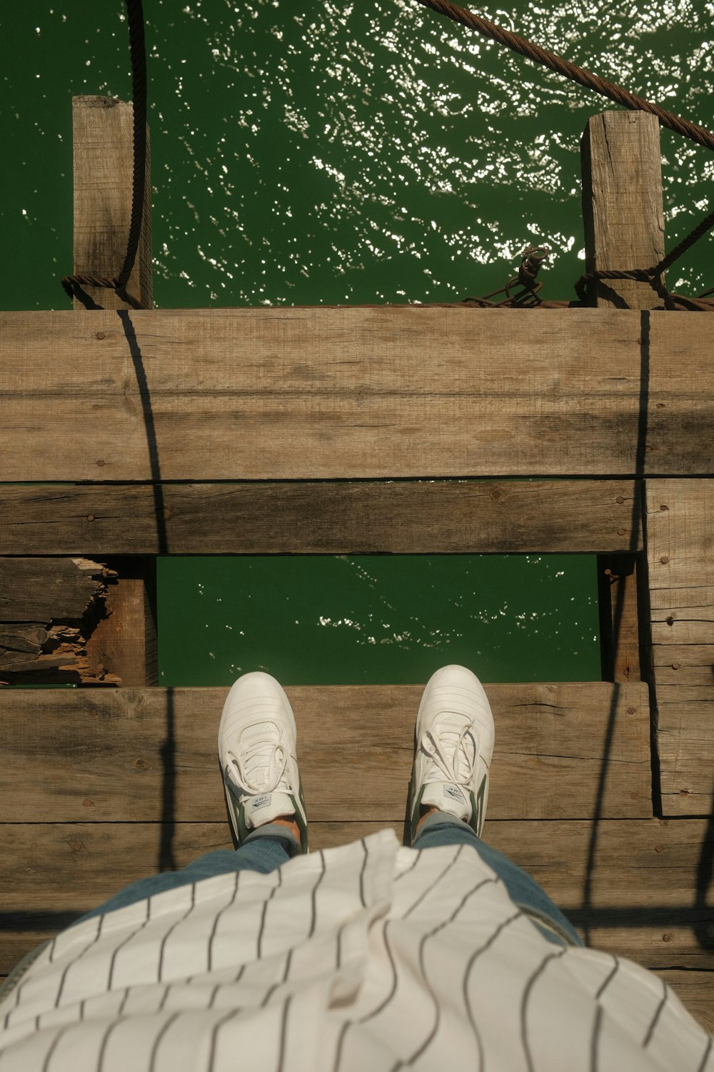 a person sitting on a dock next to a body of water