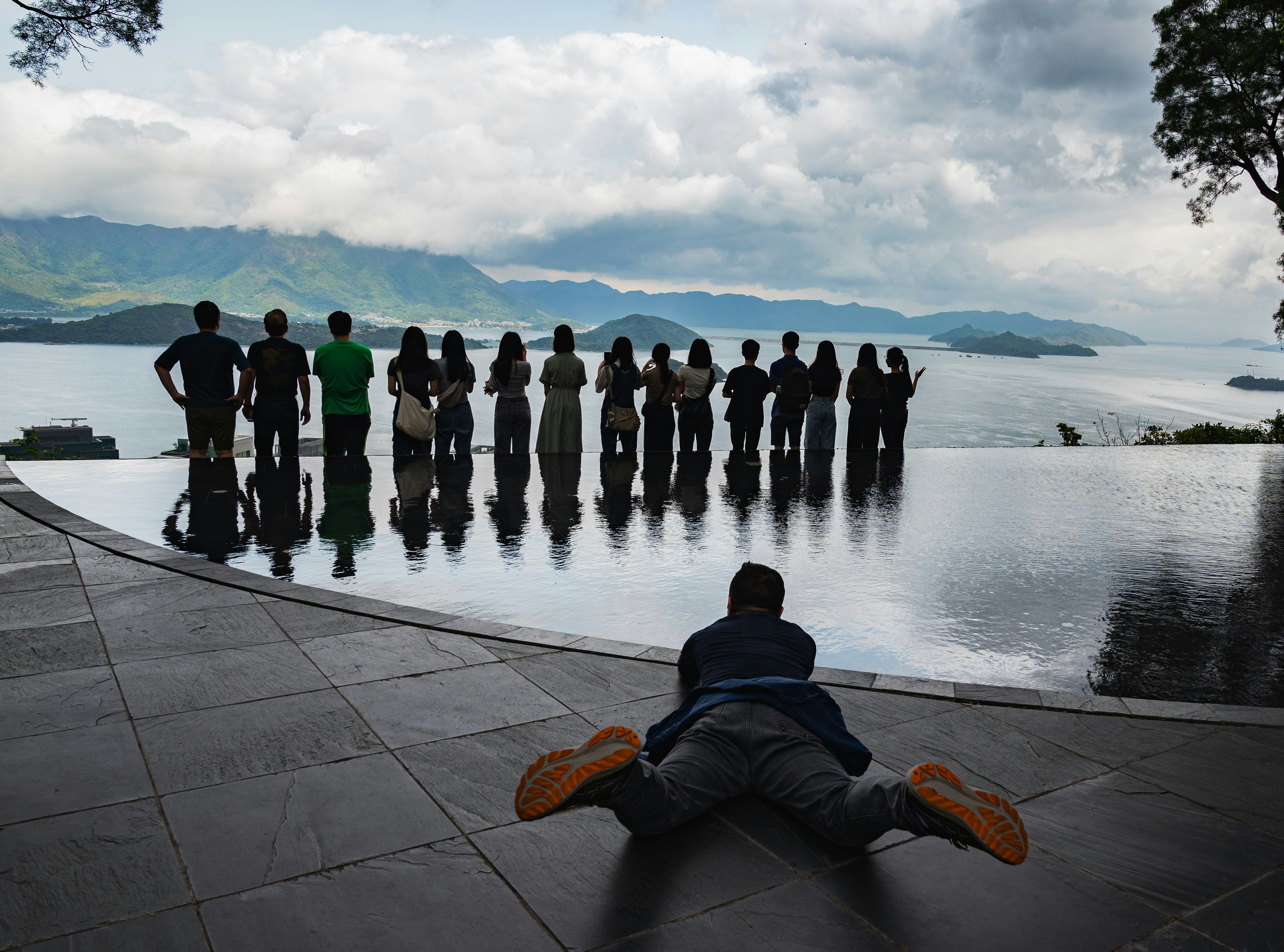 Serene infinity pool overlooking a misty mountain valley at sunrise, lone figure meditating at the pool edge