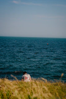 a person sitting on the edge of a cliff near the ocean