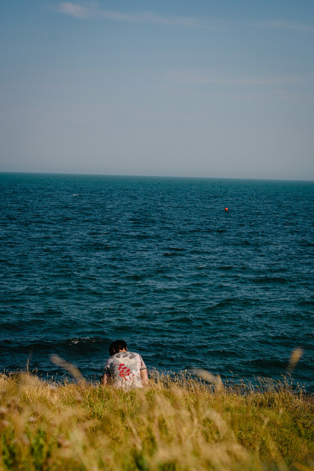 a person sitting on the edge of a cliff near the ocean