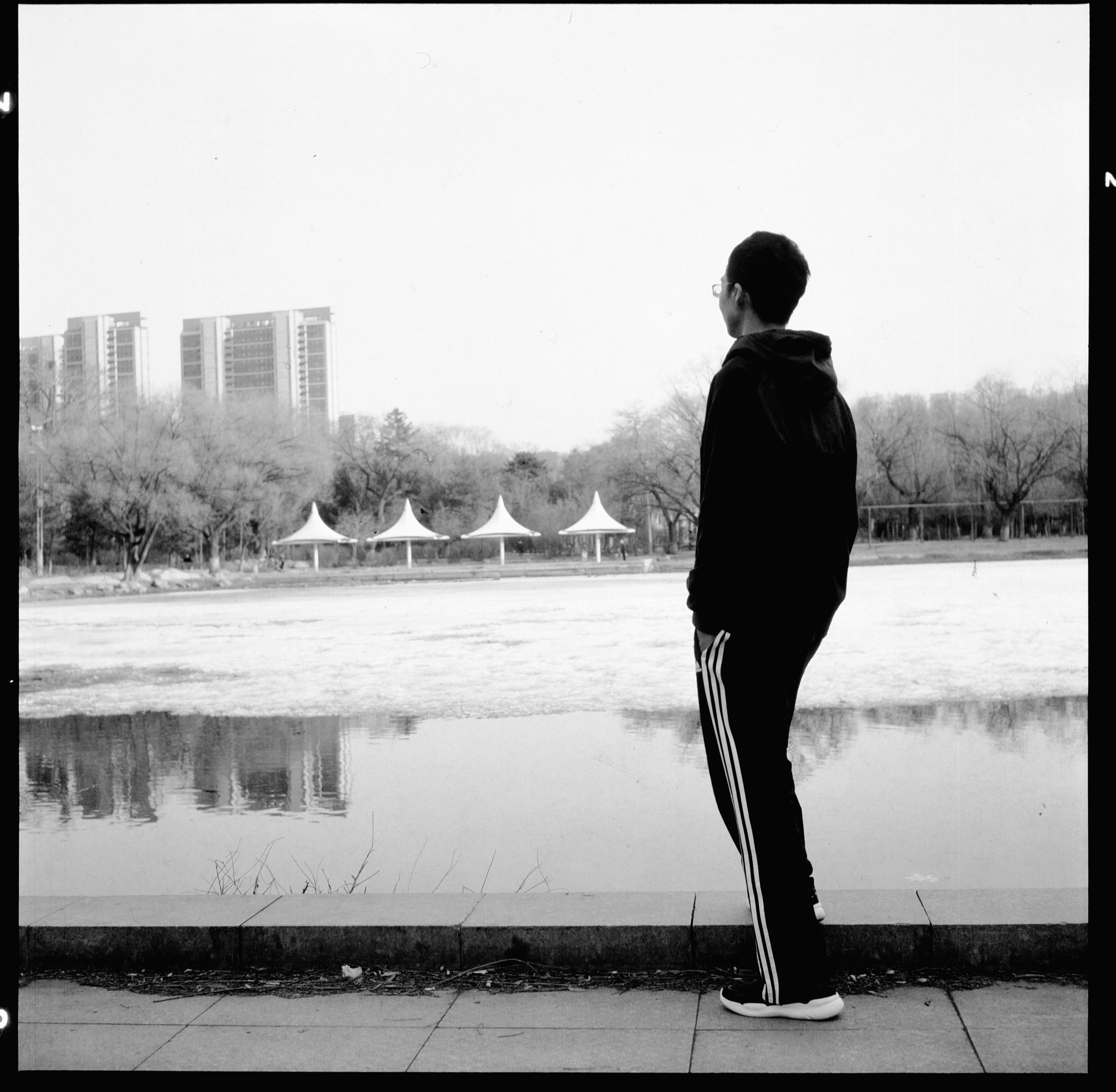 a man standing on a sidewalk next to a body of water