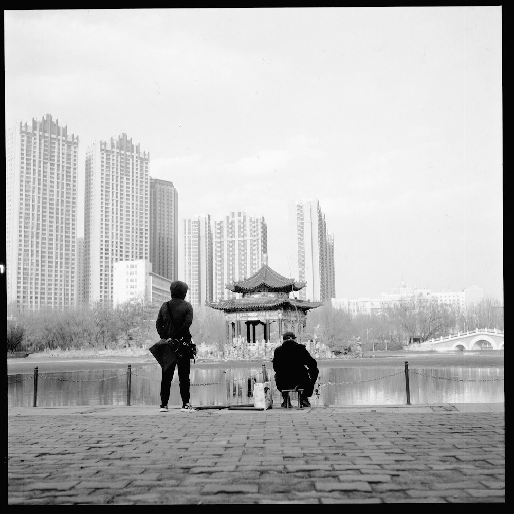 two people sitting on a bench near a body of water