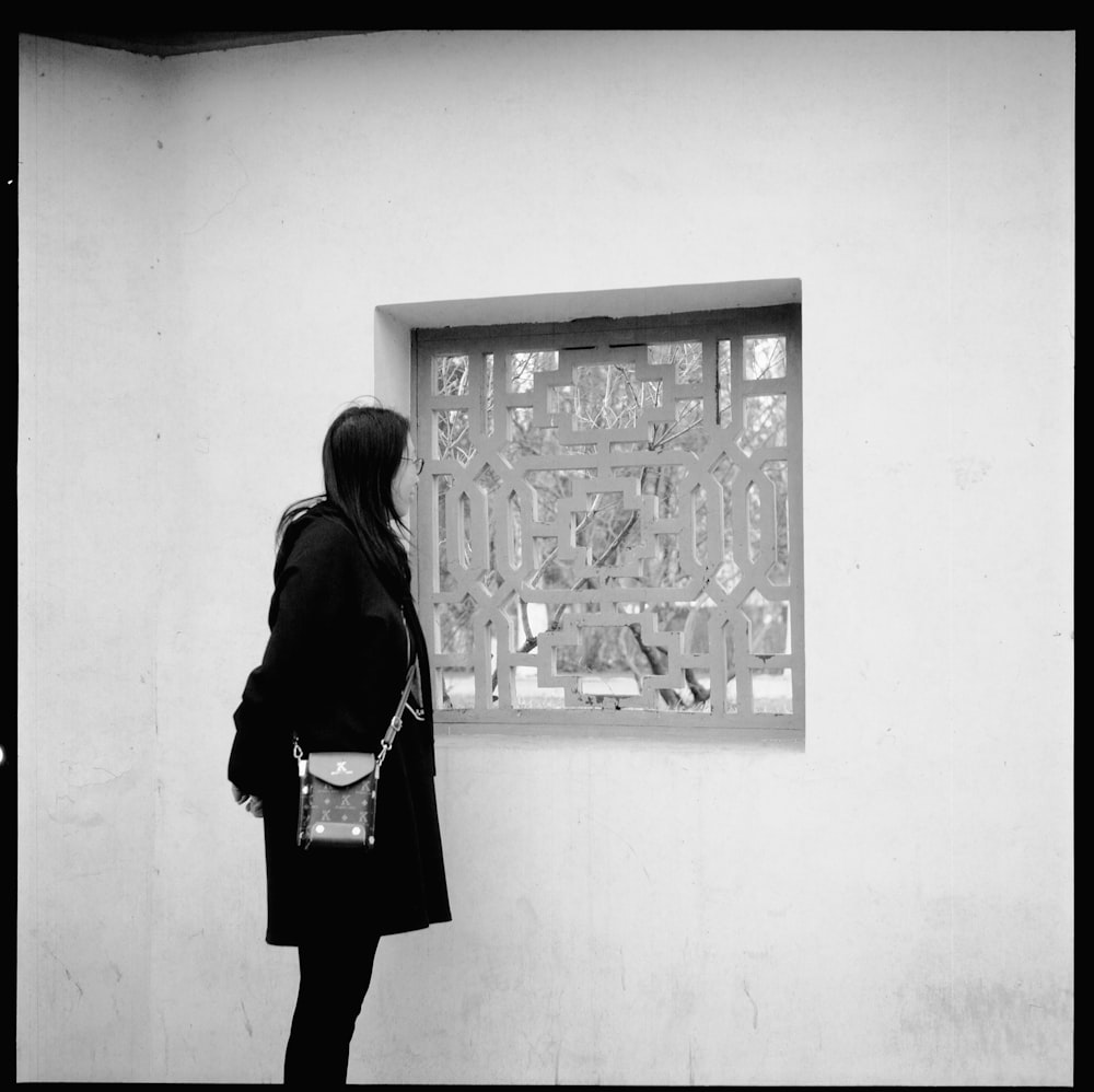 a woman standing in front of a wall with a clock on it