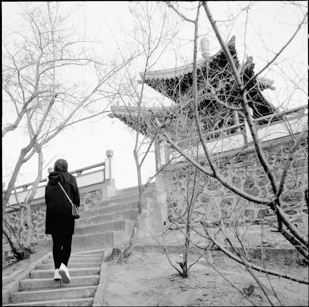 a black and white photo of a woman walking up some stairs