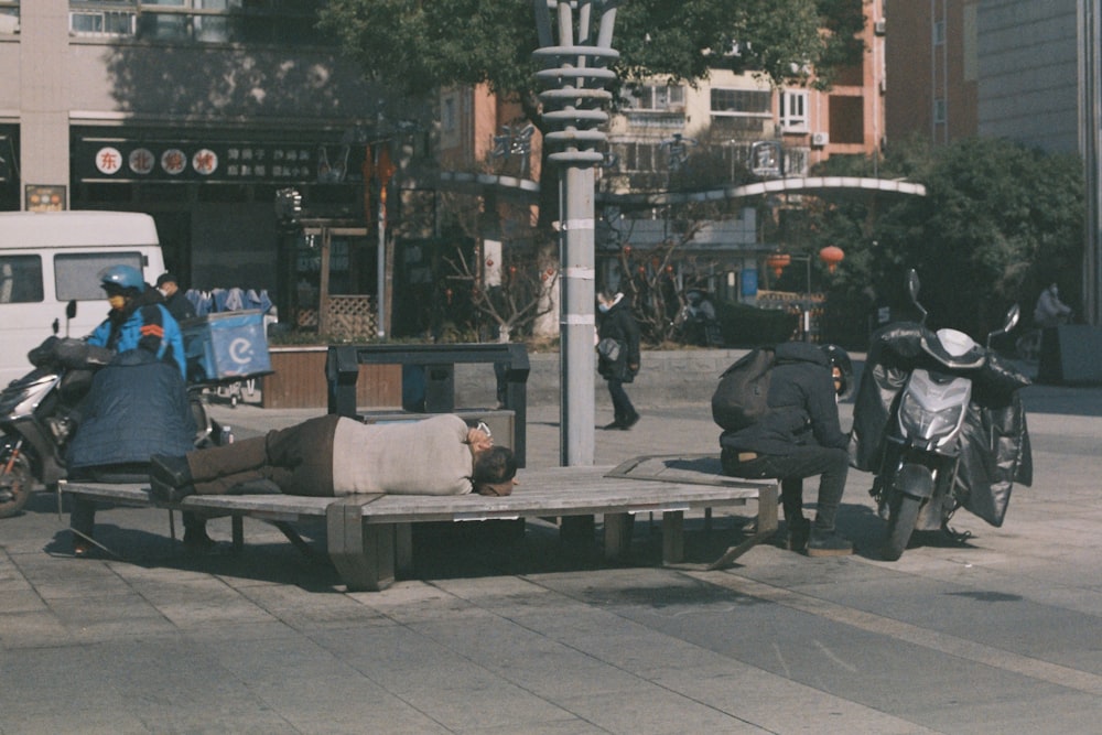 a person laying on a bench on a city street