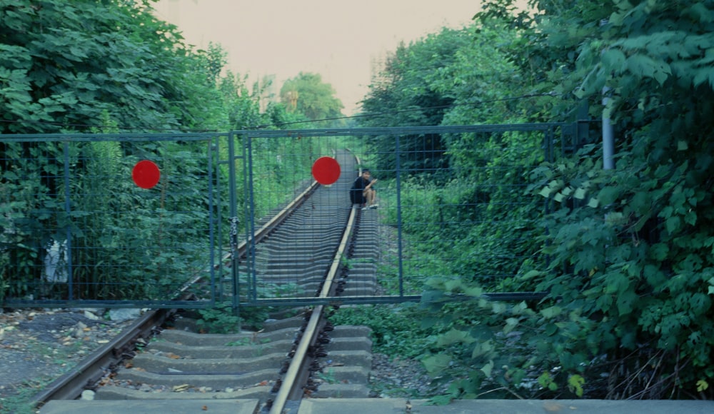 a person standing on a train track next to a gate