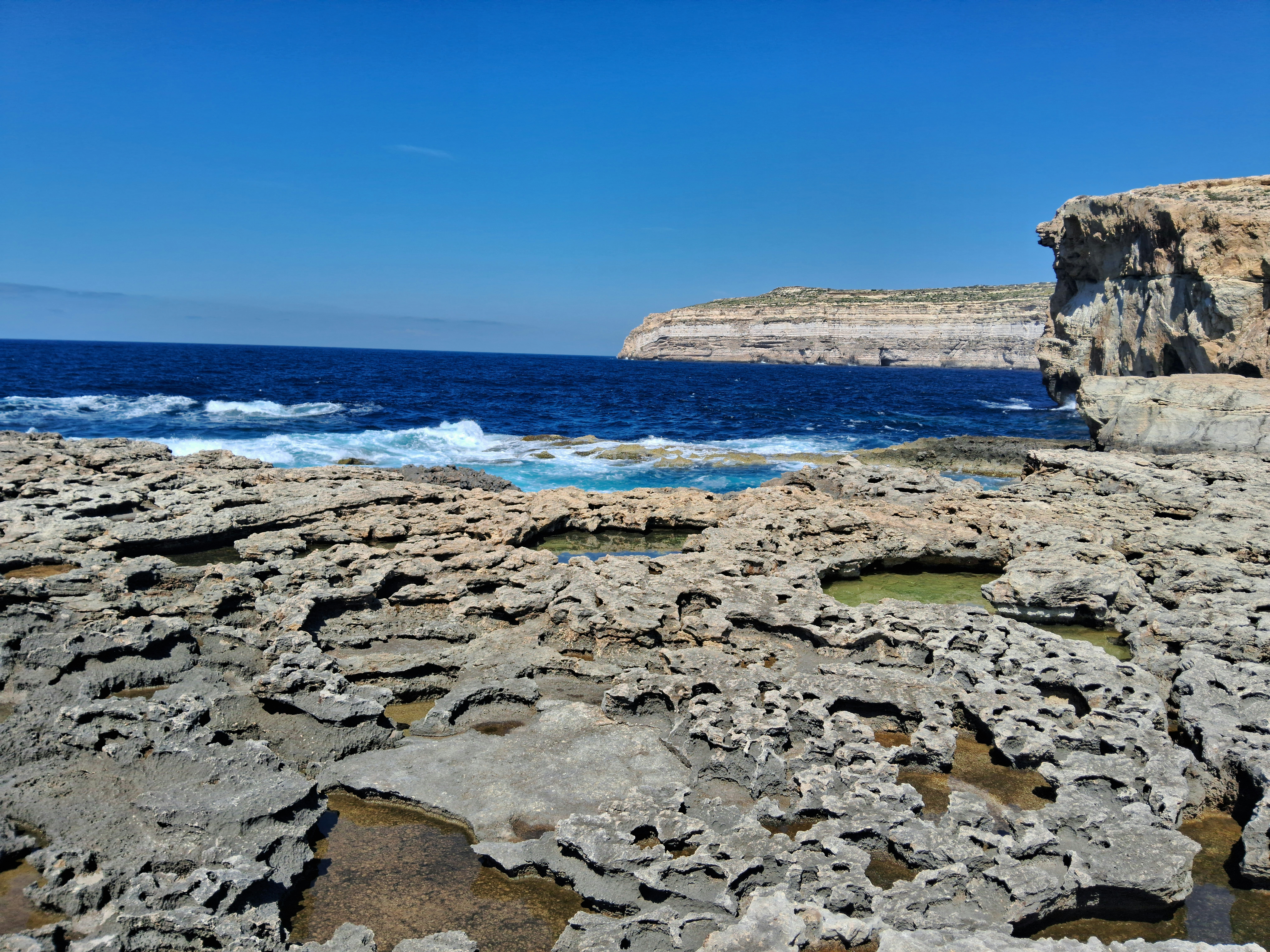 une plage rocheuse avec un plan d’eau au loin