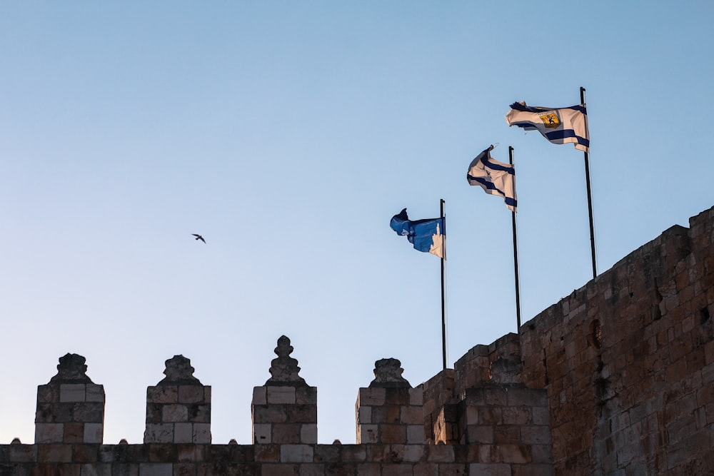 a group of flags flying on top of a stone wall