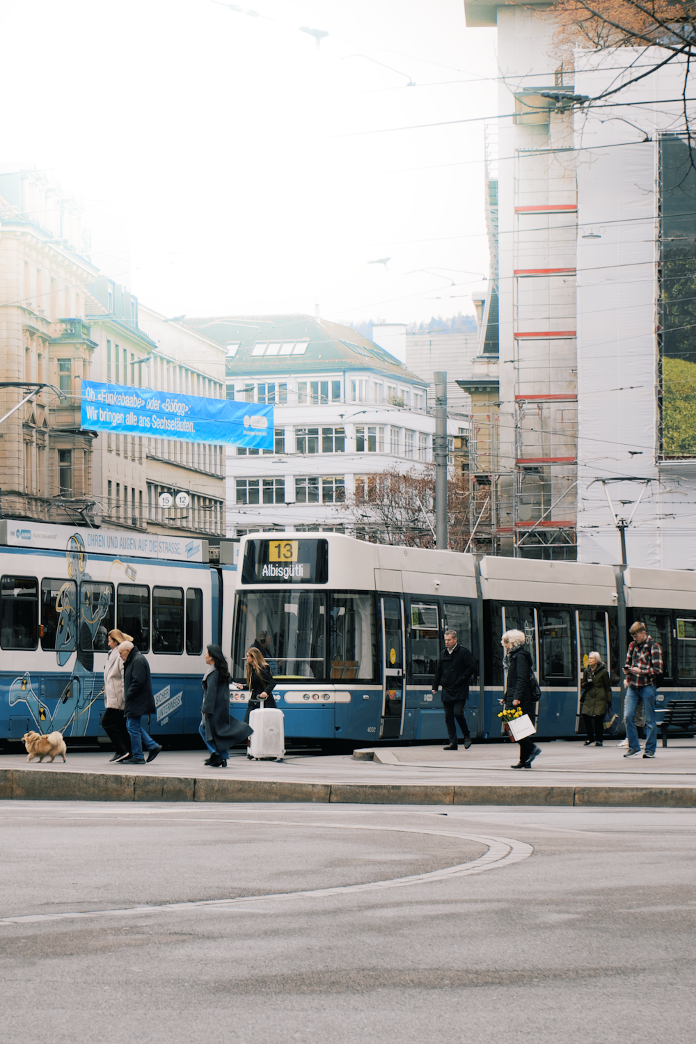 a group of people standing next to a blue and white train