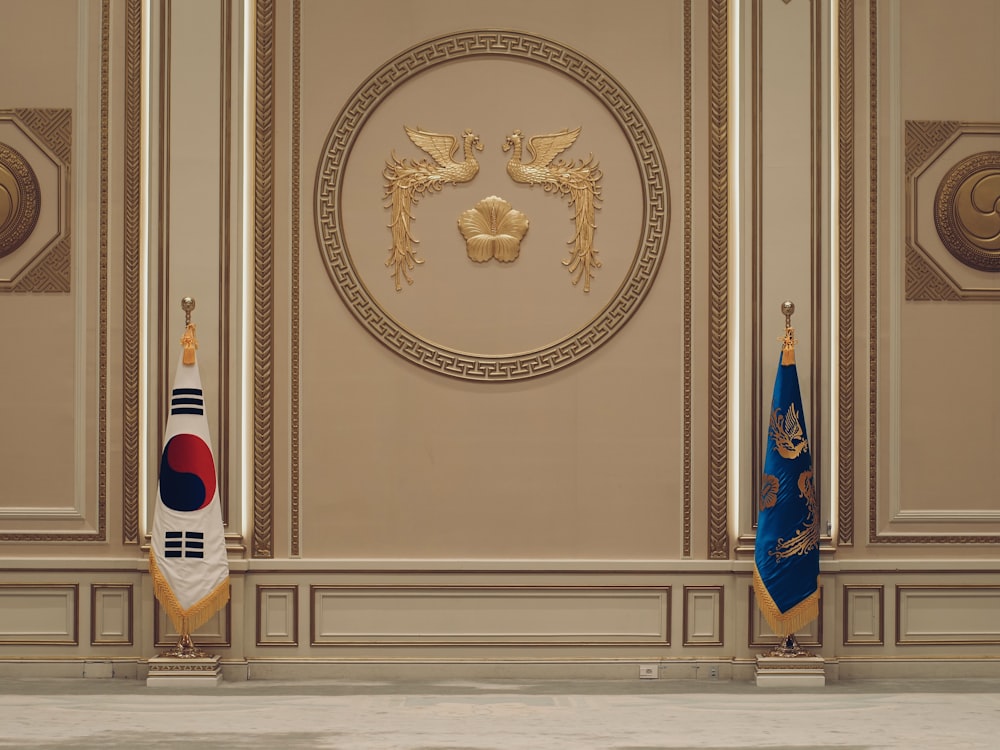 a room with two flags and a coat of arms on the wall