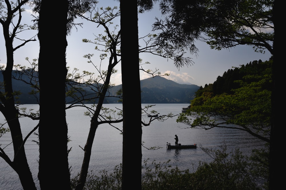 a man in a boat on a lake surrounded by trees