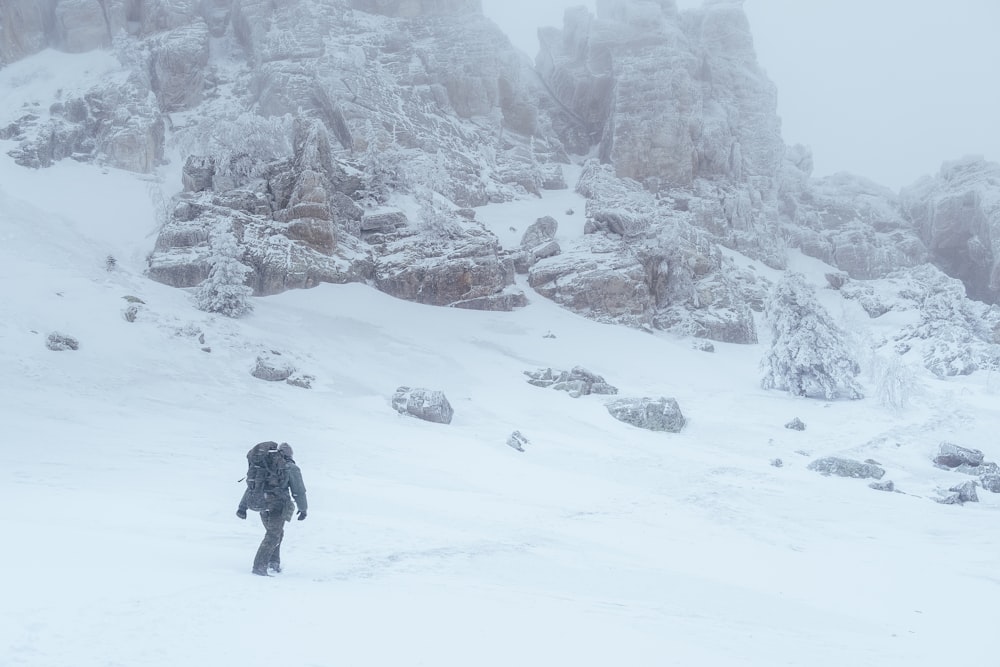 a person walking through the snow in front of a mountain