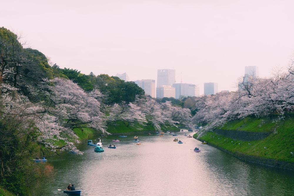 a group of boats floating down a river next to a lush green hillside