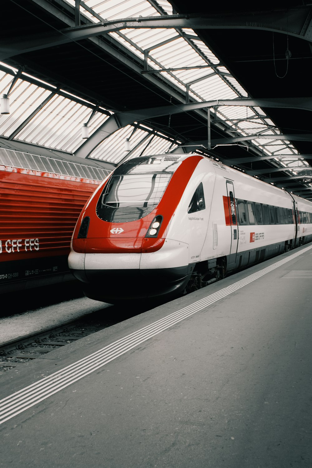 a red and white train traveling through a train station
