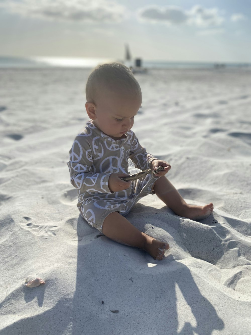 a baby sitting in the sand playing with a toy