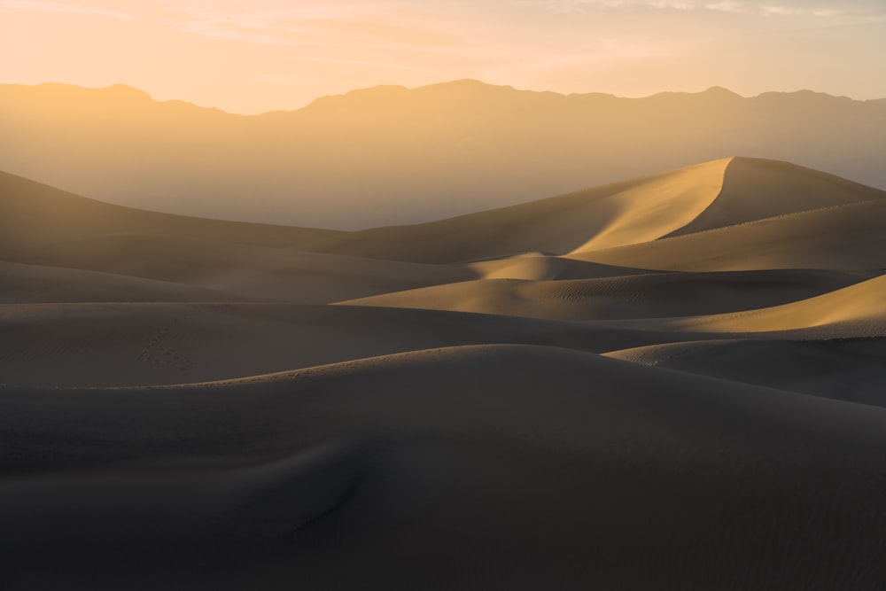 a desert with sand dunes and mountains in the background