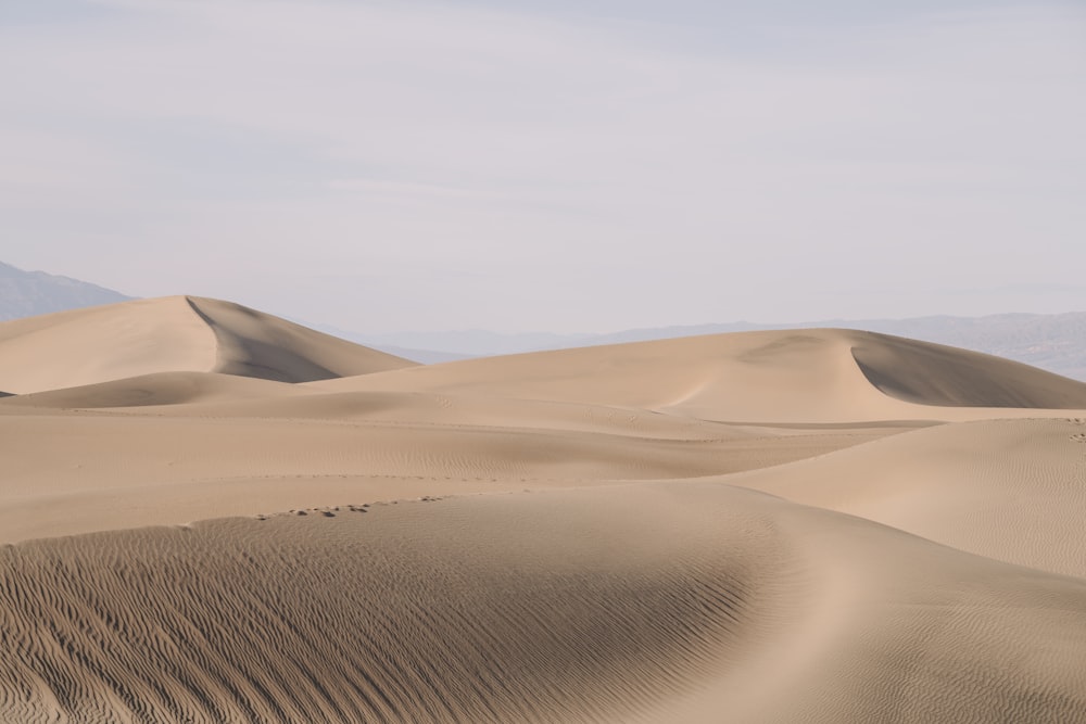 a group of sand dunes with mountains in the background