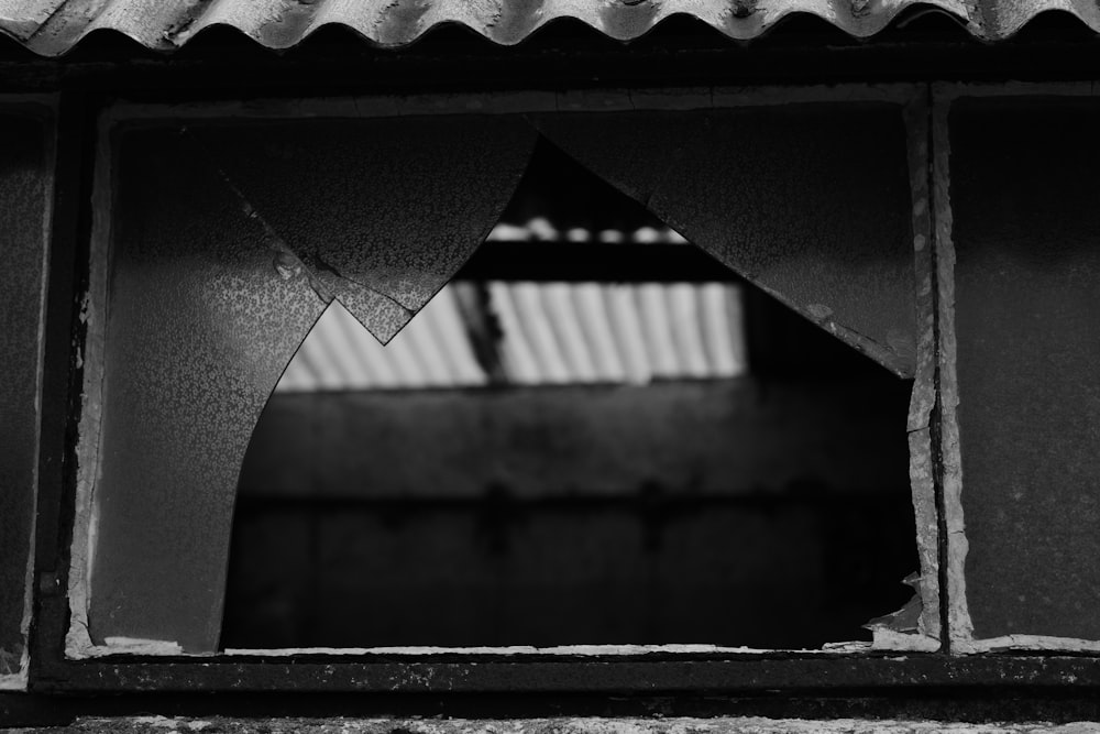 a black and white photo of a broken window