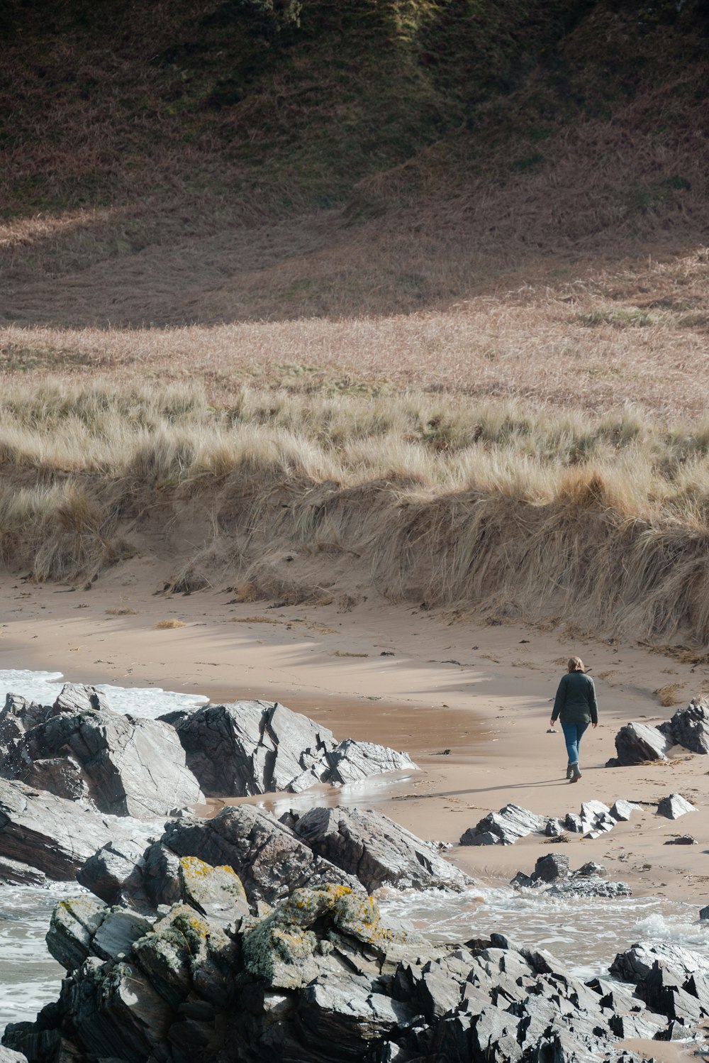 una persona caminando en una playa junto a un cuerpo de agua