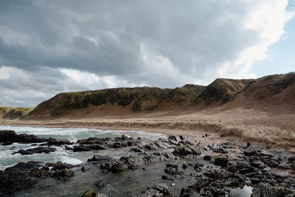 una playa rocosa con un cuerpo de agua en primer plano
