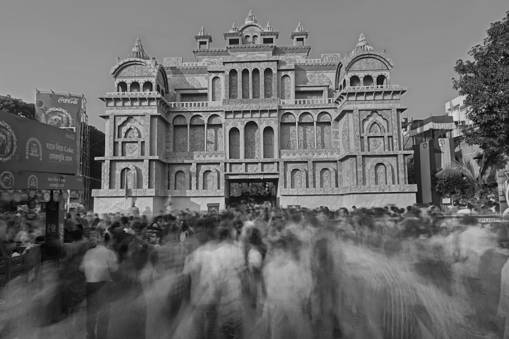 a black and white photo of people walking in front of a building