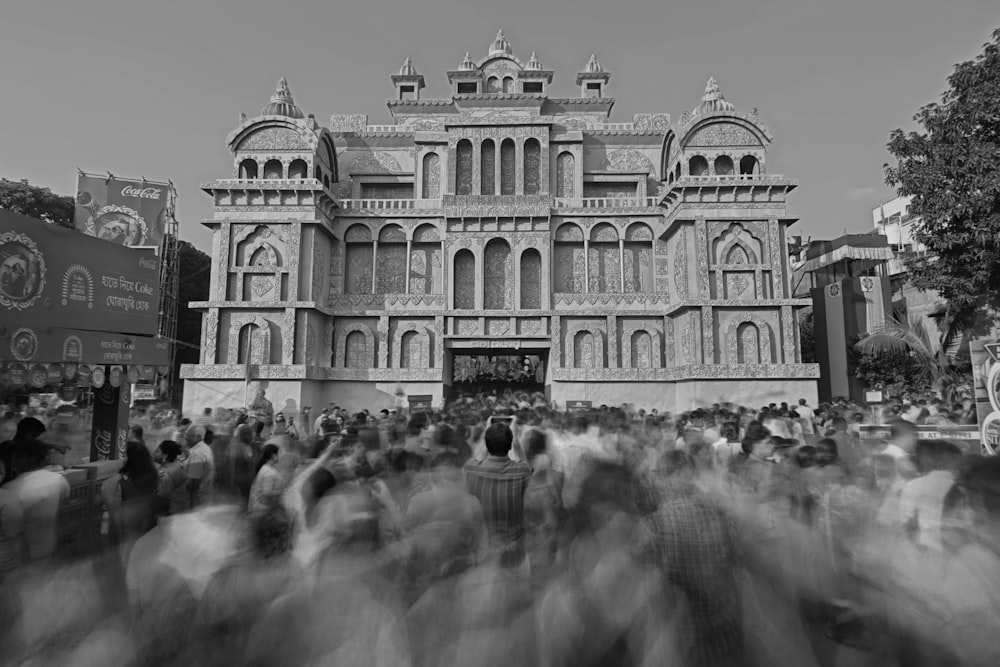 a black and white photo of a crowd of people in front of a building