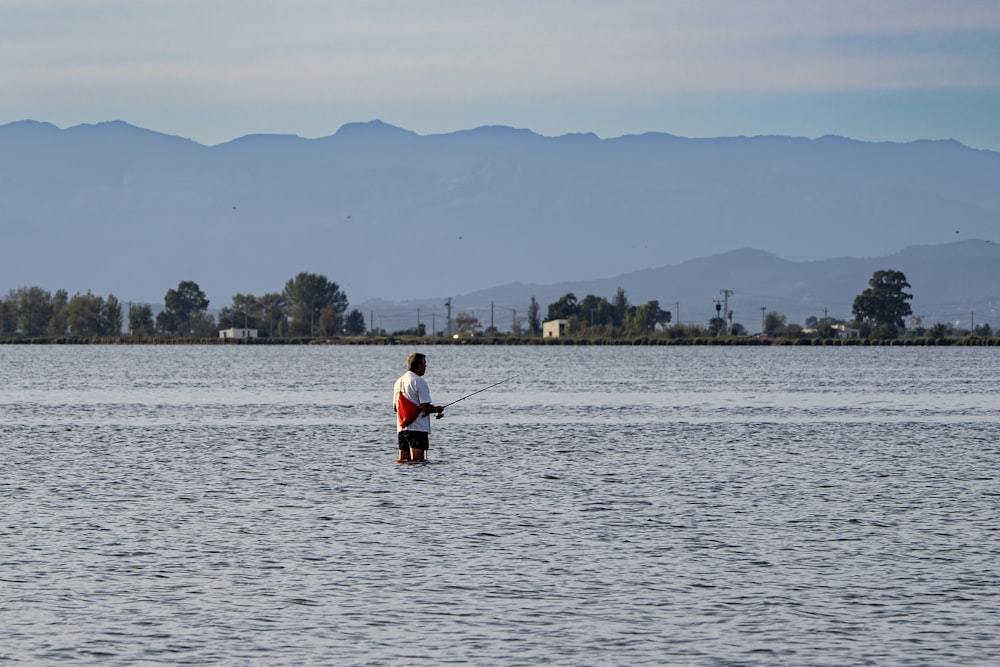 a man standing in the water holding a fishing pole