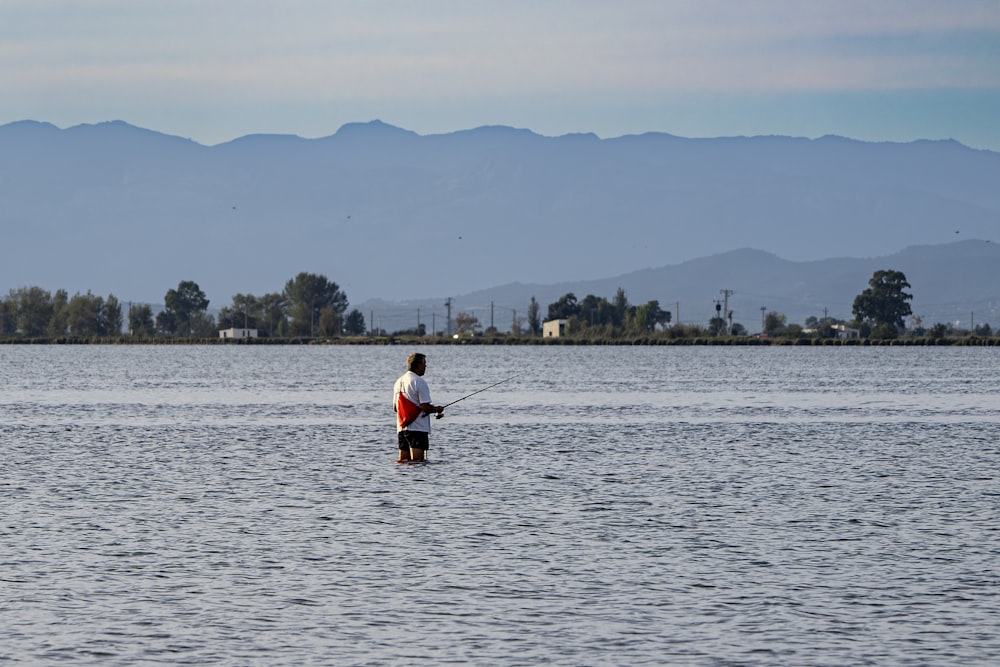 un homme debout dans l’eau tenant une canne à pêche
