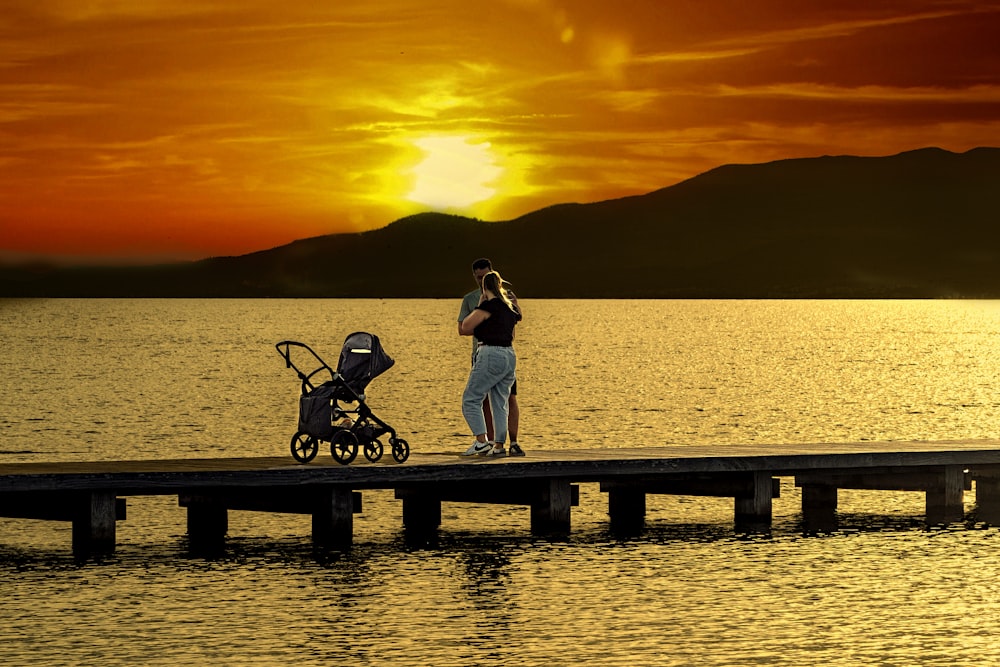 a man standing on a pier next to a baby stroller