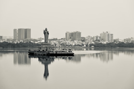 a statue of a person standing on top of a body of water