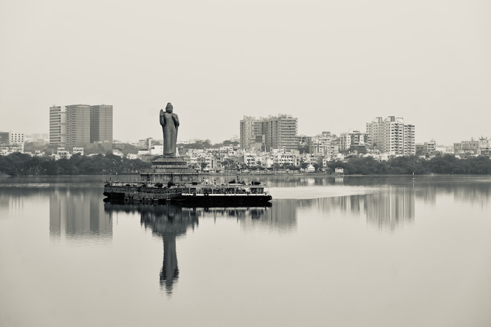 a statue of a person standing on top of a body of water
