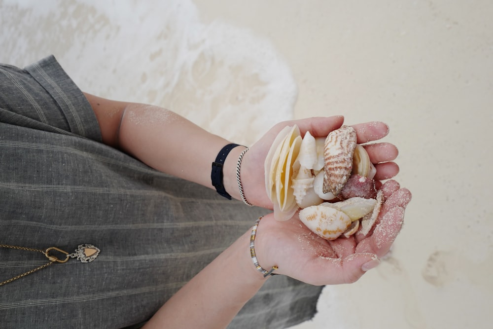 a woman holding a bunch of seashells in her hands