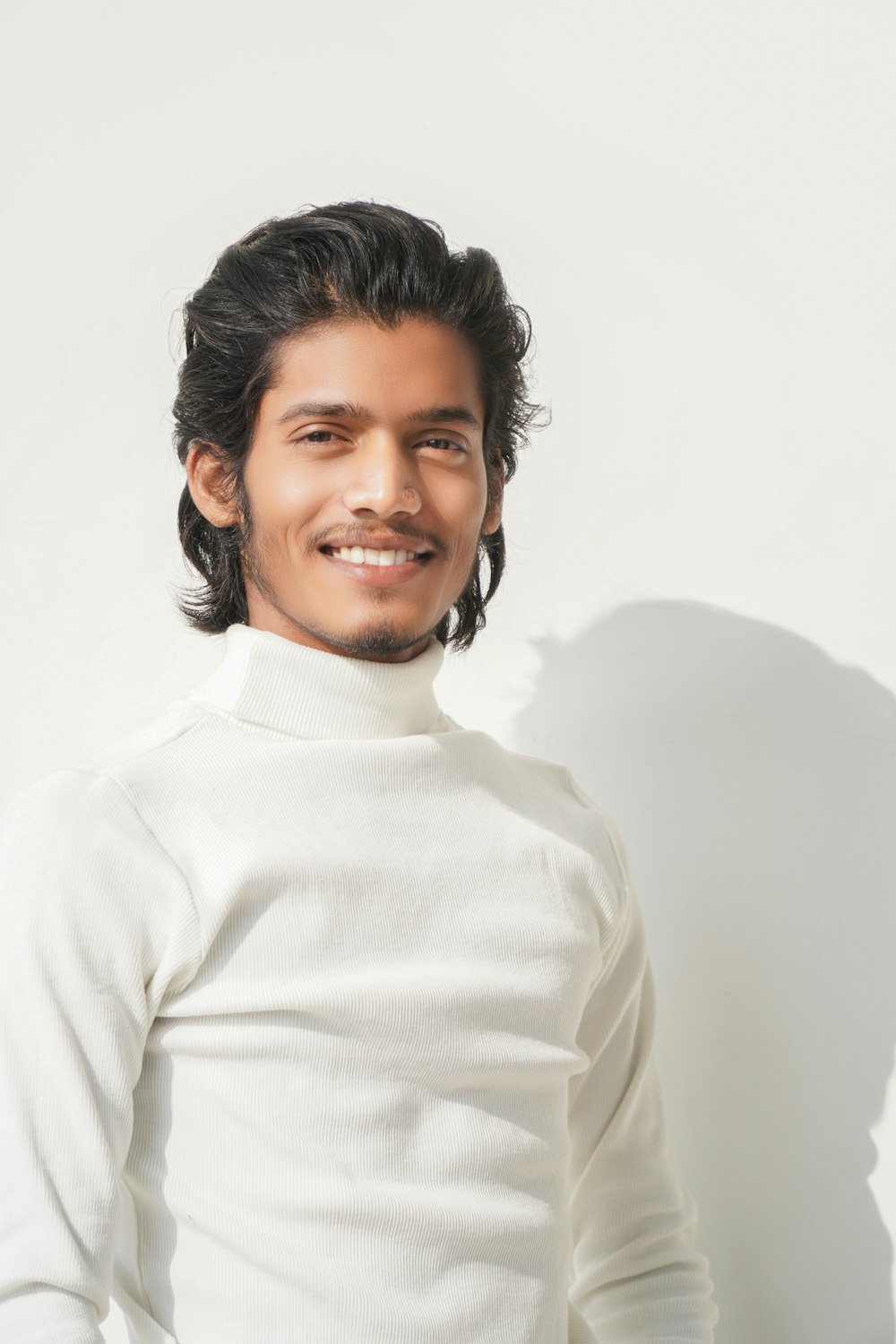 a man in a white shirt smiling for the camera