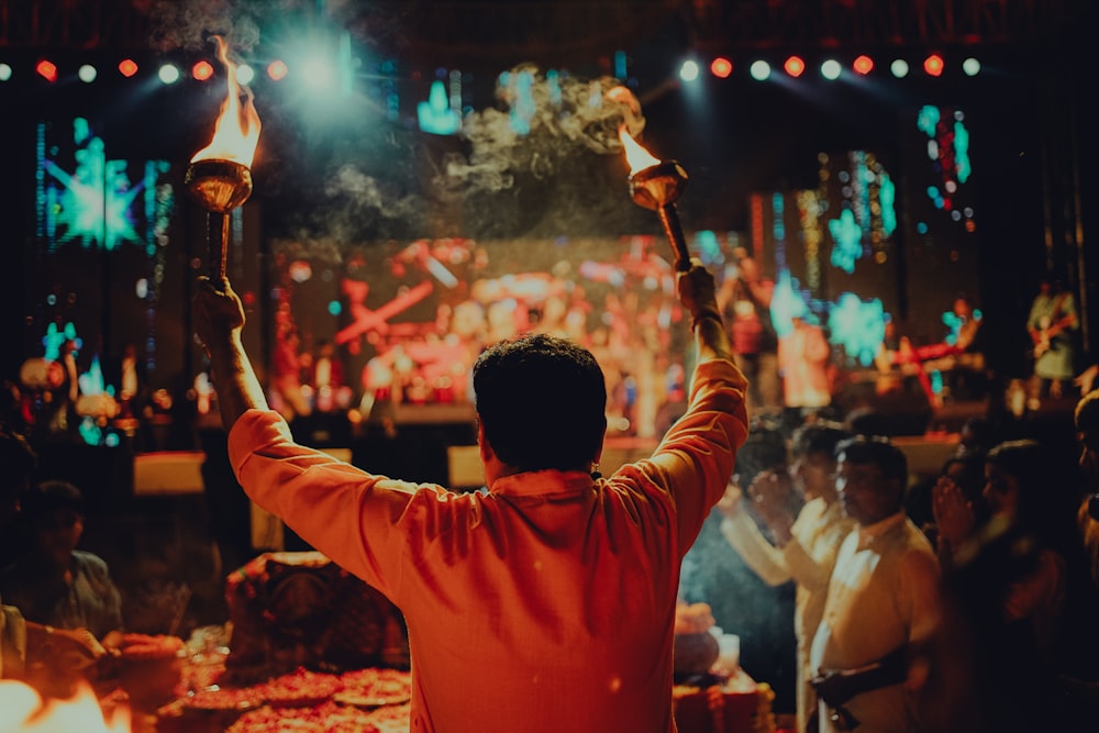 a man holding two torches in front of a crowd of people