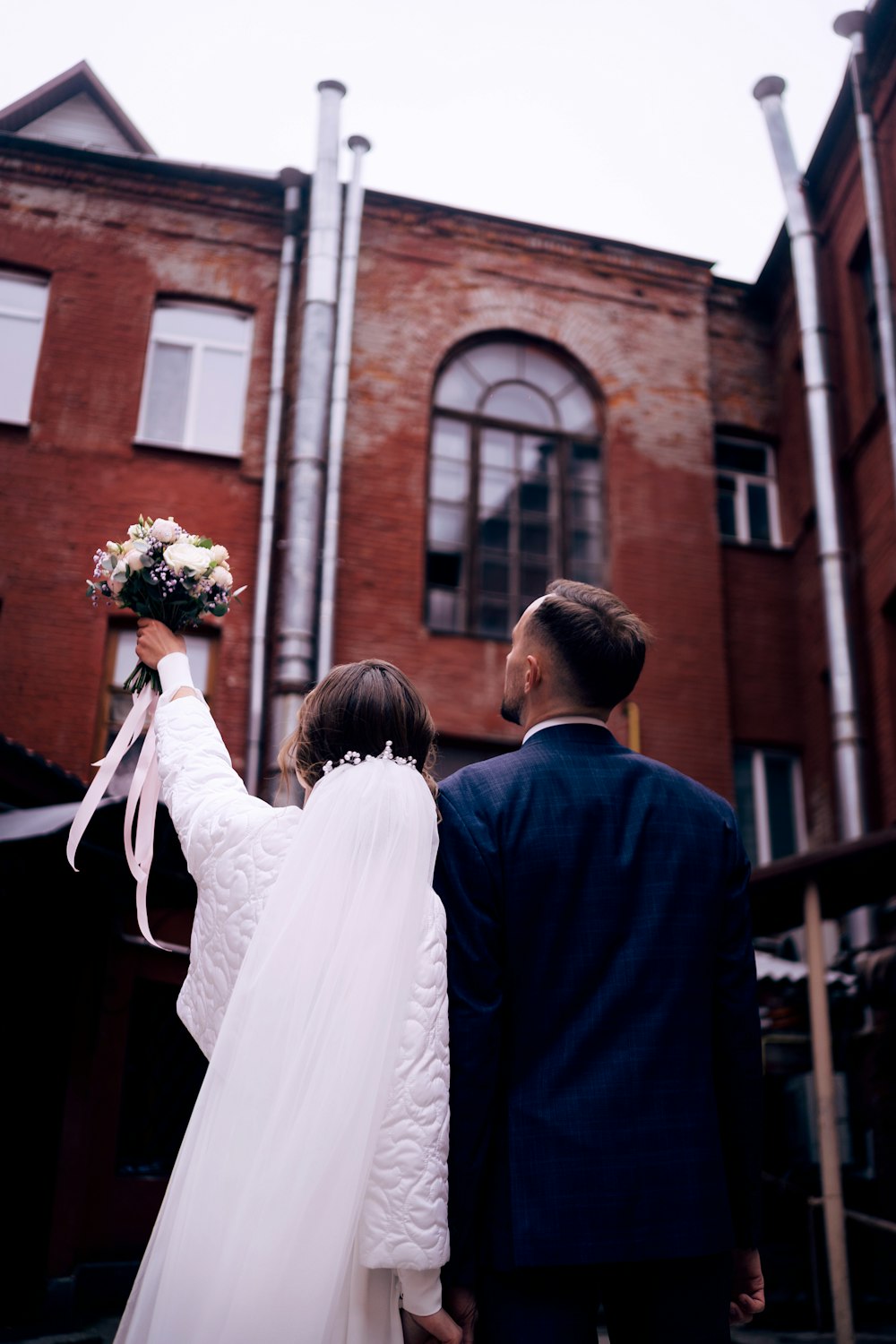 a bride and groom walking towards a building