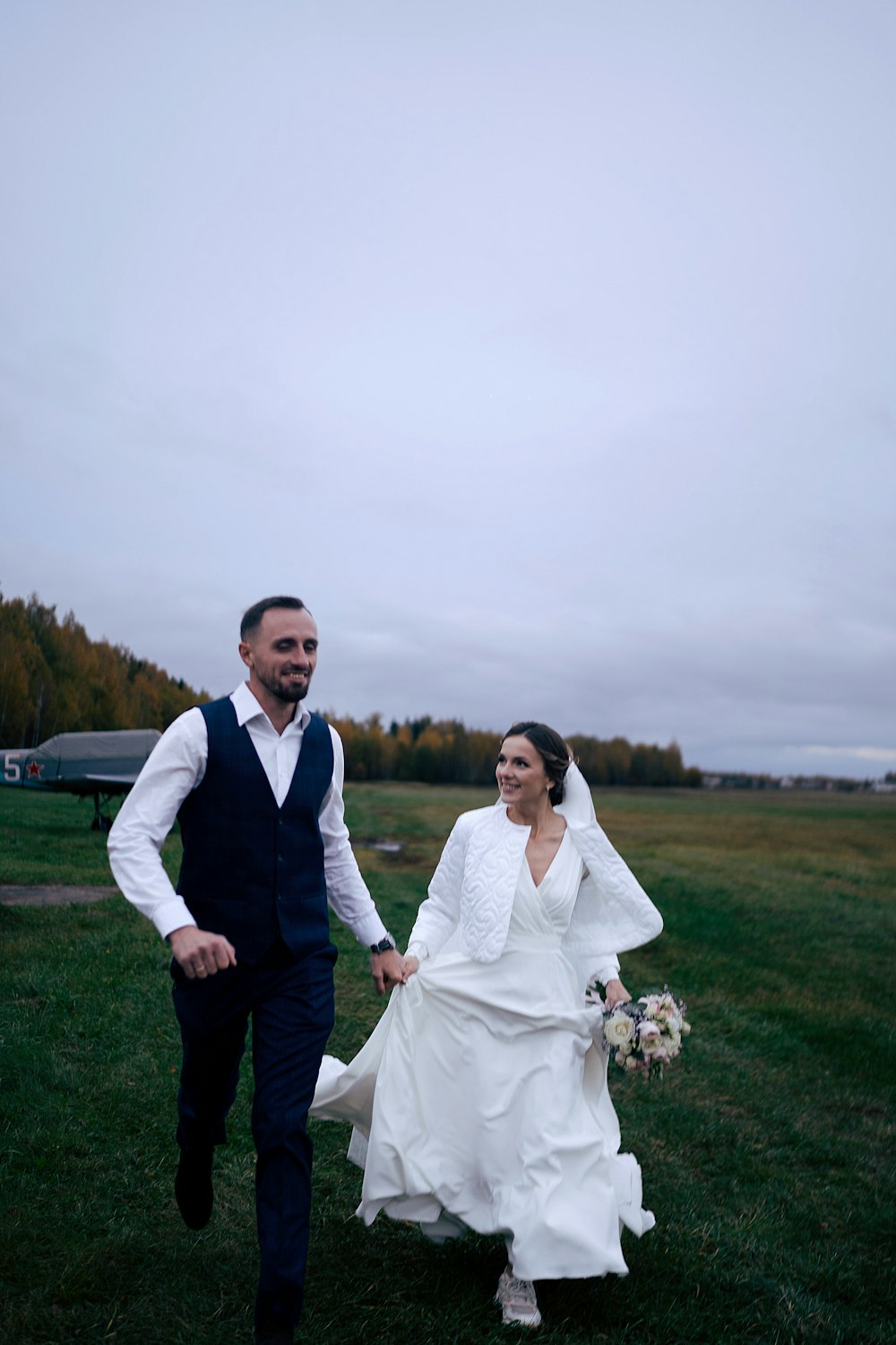 a bride and groom walking through a field