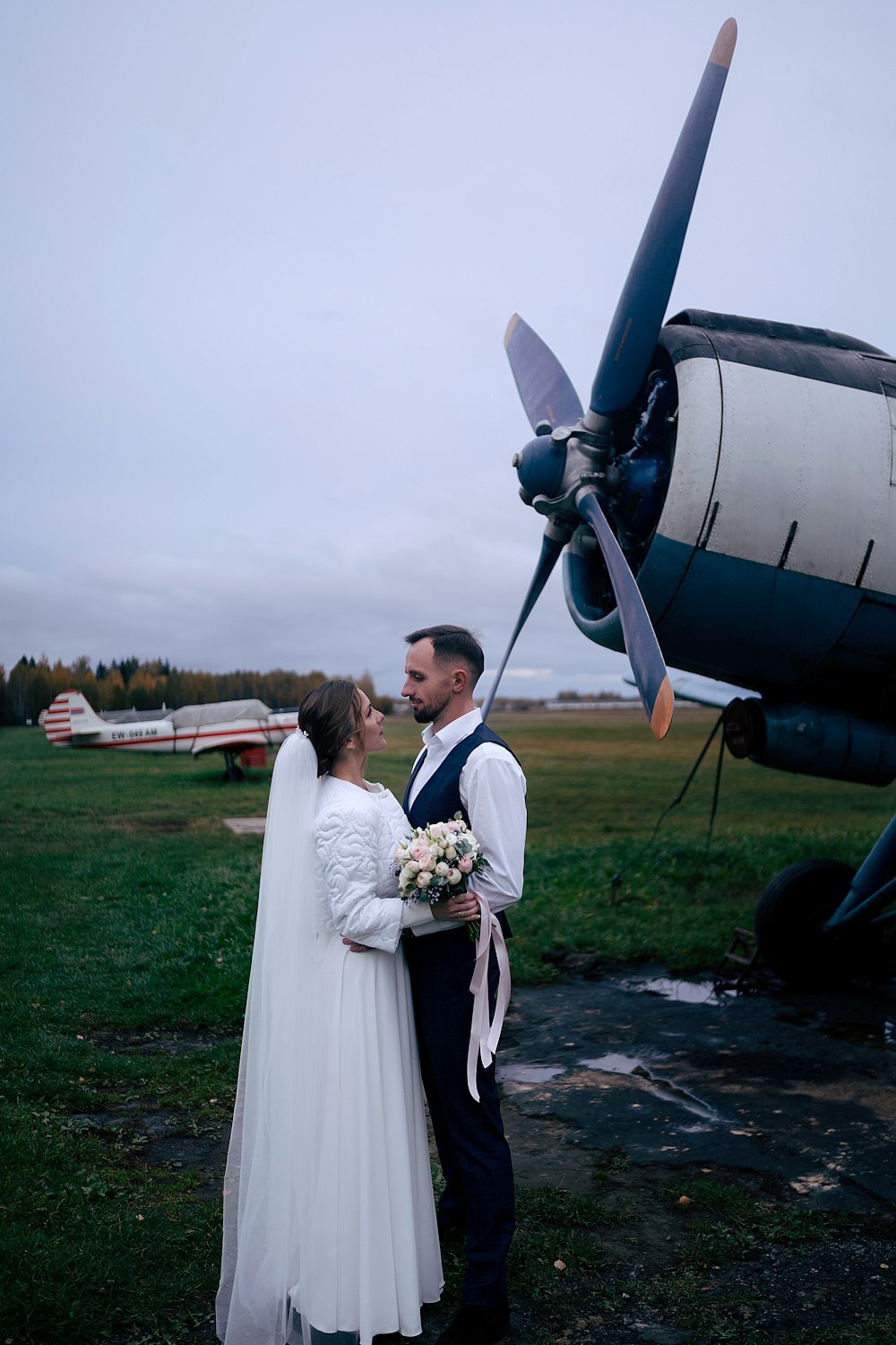 a bride and groom standing in front of an airplane