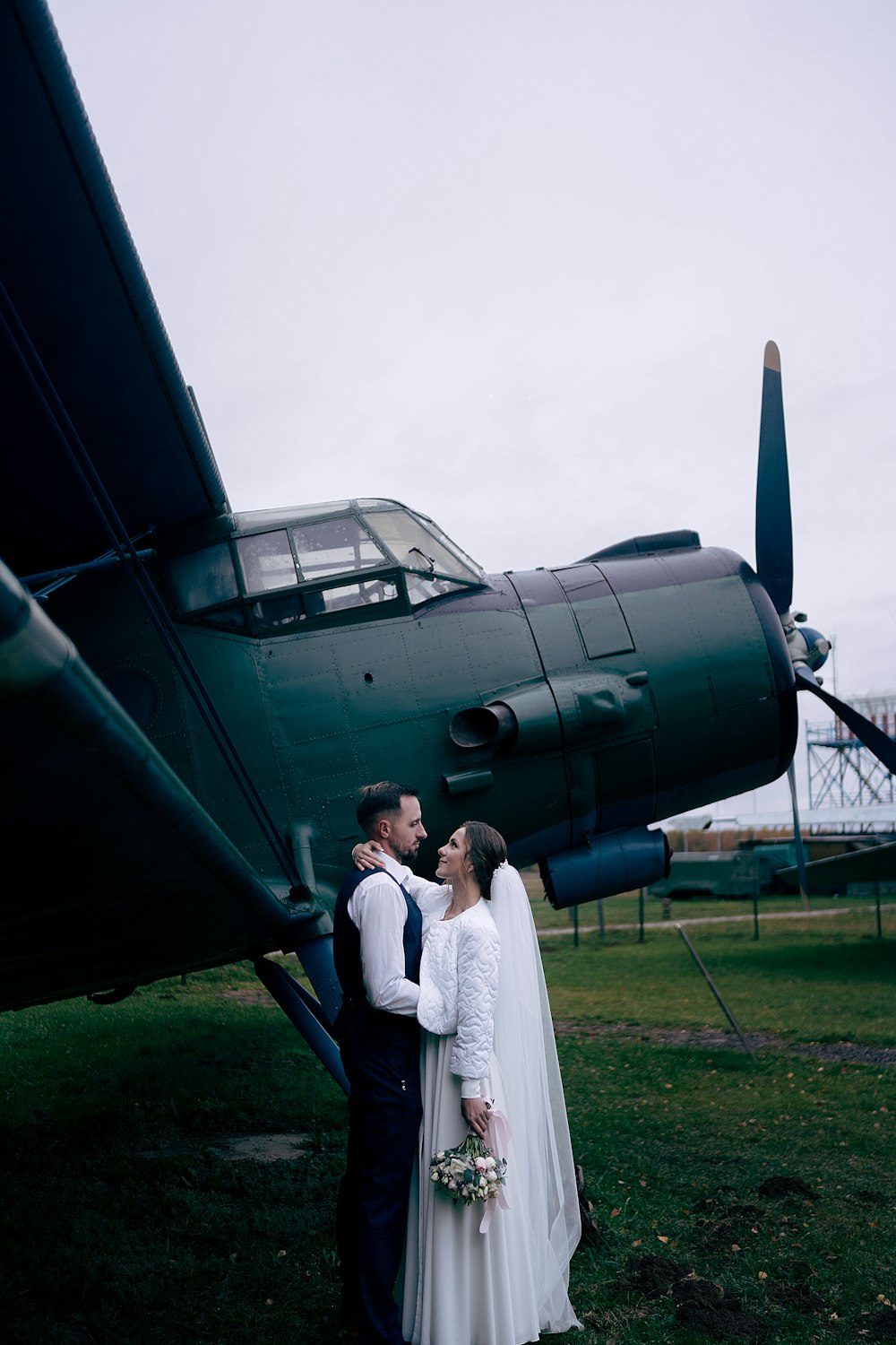 a bride and groom standing in front of an airplane