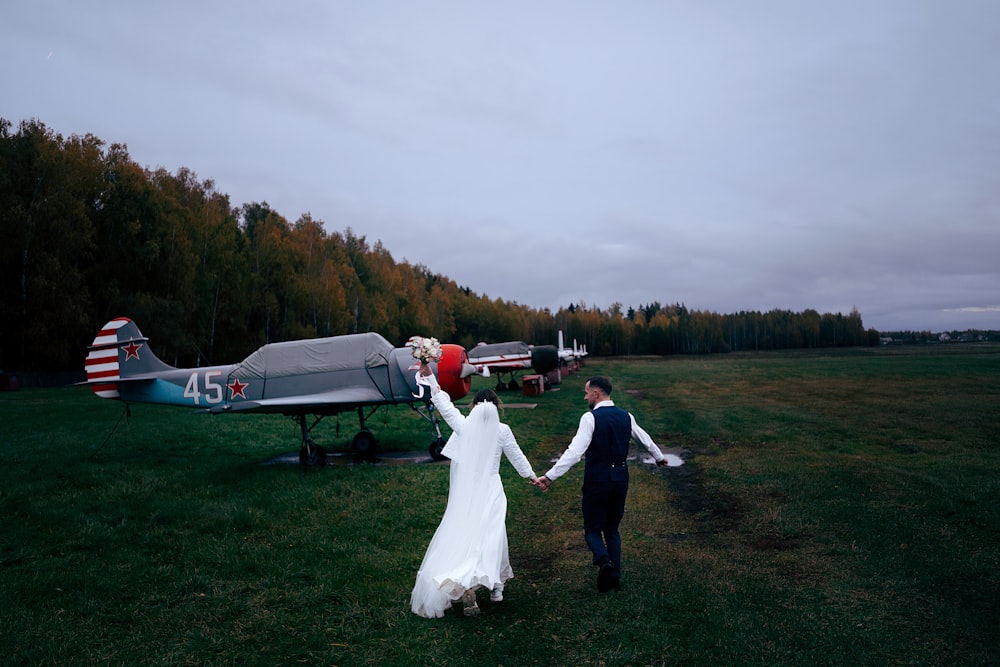 a bride and groom holding hands in front of an airplane