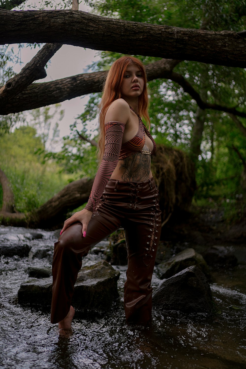 a woman standing in a river next to a tree