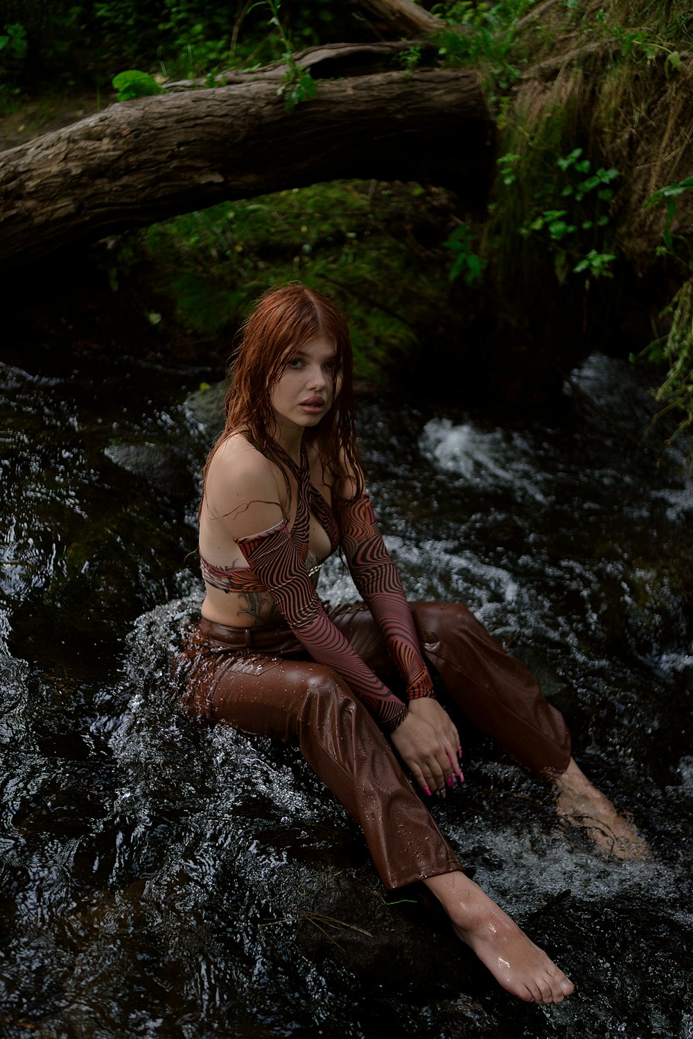 a woman sitting on a rock in a river